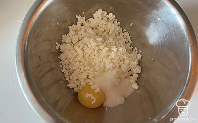 В миске соедините творог, желток куриного яйца и 1 столовую ложку сахара.