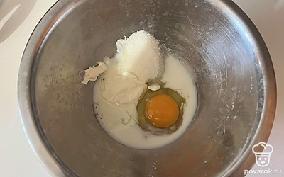 В емкости соедините яйцо, молоко, сметану и 1 столовую ложку сахара. 