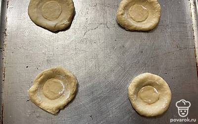 Форму для выпекания смажьте растительным маслом, перенесите на нее тесто и при помощи стакана сделайте в каждой лепешке небольшое углубление.