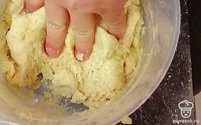 К смеси добавьте муку, перемешивайте всё вилкой, потом руками. Тесто готово, когда перестает липнуть к рукам.