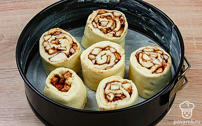 Сверните тесто с начинкой в плотный рулет и разрежьте на 6 частей. Смажьте форму для выпечки сливочным маслом. Выложите в нее получившиеся заготовки. Отправьте синнабоны выпекаться в духовку на 30-40 минут при 180°С.