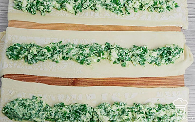 Тесто раскатайте в пласт толщиной в 3 мм. И нарежьте на полоски шириной 6-7 см. На каждую полоску положите начинку. Начинку выкладывайте, оставляя с краев по 2 см.