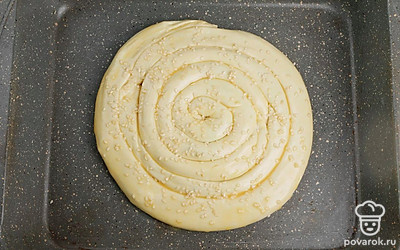 Форму смажьте маслом. Укладывайте колбаску закручивая ее. Одна за другой. Хвостик одной колбаски- это продолжение другой. Плотненько сверните колбаски. Яйцо размешайте вилкой и смажьте сверху улитку. Посыпьте кунжутом.