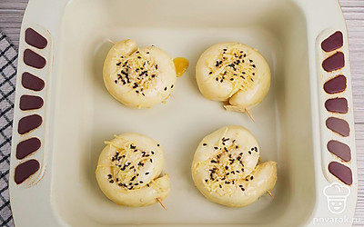 Выложите улиток на противень, предварительно смазав его растительным маслом или застелив бумагой для выпечки. Взбейте яйцо и смажьте им булочки. Сверху посыпьте кунжутом.