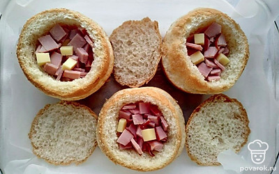 У булочек срежьте верхушку, удалите мякиш. Выложите в середину булочки подготовленную ветчину и сыр. Залейте подготовленной яичной смесью. Накройте верхушкой, как крышкой.