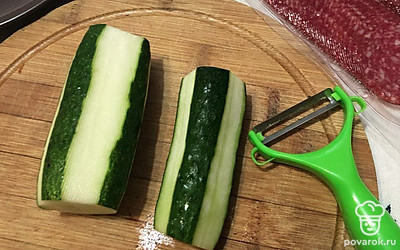 Овощечисткой снимаем кожуру с огурцов, оставляя зеленые полосы для красоты.