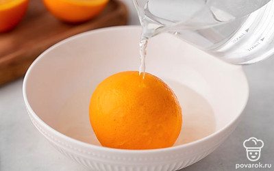 Выложите апельсины в небольшую миску. Чтобы уменьшить горечь корки, обдайте фрукт кипятком.