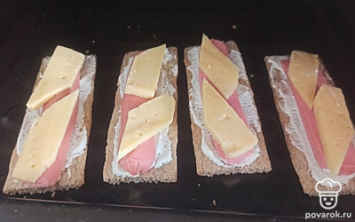 Нарезаем сыр на небольшие ломтики. Кладем поверх сосисок и ставим в разогретую до 180 градусов духовку на 15 минут. 