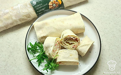 Можно оставить на некоторое время в холодильнике для того, чтобы лаваш лучше пропитался. Разрежьте рулет на порции. Украсьте зеленью.