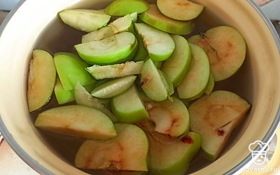 Воду поставьте на огонь и добавьте порезанные на дольки яблоки.