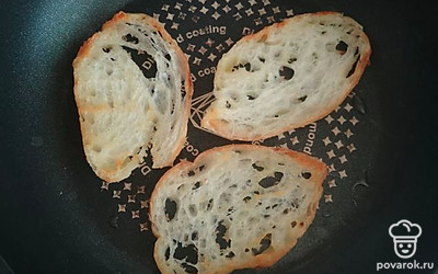 Багет нарезать тонкими ломтиками и обжарить на сухой сковороде.