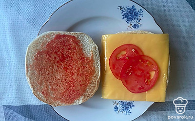 На сыр выложите тонко нарезанные ломтики томата.