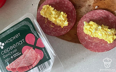 Возьмите нарезанные ломтики сервелата, выложите начинку в центр.