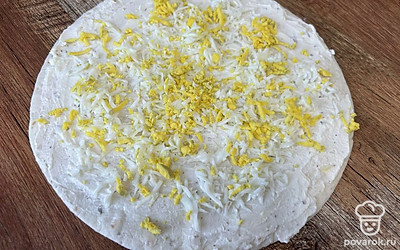 Яйцо натрите на мелкой терке, распределите по тортилье.