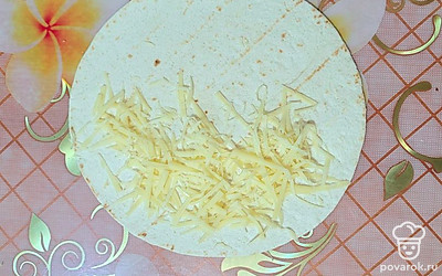 На одну половину тортильи выложить тертый сыр.