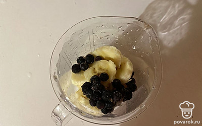 В чаше блендера соедините чёрную смородину и нарезанный банан.