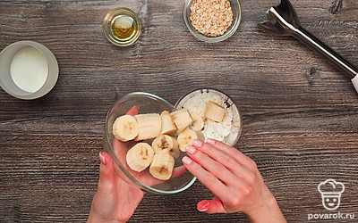 Поместите в чашу блендера творог и банан. Добавьте мед и овсяные хлопья. Включите устройство и перемешивайте ингредиенты до однородности чуть меньше минуты.