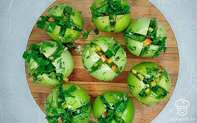 Зелень мелко порубит и поместите в миску. Перец почистите от семян, порежьте мелкими кубиками, добавьте в миску с зеленью. В измельченные ингредиенты выдавите через пресс очищенный чеснок. Все хорошо перемешайте. Помидоры надрежьте крест-накрест, но не до конца. В разрезы вложите измельченные ингредиенты.