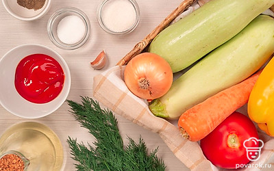 Подготовьте продукты для кабачковой икры в духовке: Помойте все овощи и зелень. Репчатый лук, чеснок и морковь почистите. Морковь нарежьте тонкими кружочками, репчатый лук — произвольно, чеснок пропустите через пресс. У сладкого перца вырежьте плодоножку, удалите семена. Укроп мелко порубите.