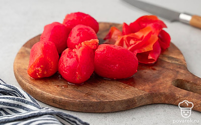 Вырежьте из помидоров места крепления плодоножек, положите овощи в жаропрочную миску. Вскипятите в чайнике 1-1,5 стакана воды, залейте ей помидоры. Оставьте помидоры в горячей воде на 2-3 минуты. Налейте в другую миску холодную воду, переложите в нее помидоры на 1 минуту. Затем снимите с помидоров кожицу.