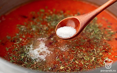 Всыпьте в кастрюлю соль, сахар, красный молотый перец, кориандр и смесь сушеных трав. Все тщательно размешайте и поварите массу еще около 15-20 минут. Снимите кастрюлю с аджикой с огня.