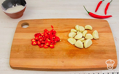 Красный перец мелко нарежьте отдельно - его лучше добавлять в аджику постепенно, чтобы не переборщить с остротой. Лук можно тоже нашинковать вручную, но удобнее будет разделить его на части и затем пропустить через мясорубку.