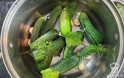 В кастрюлю выложить огурцы и листья черной смородины. Добавить черный перец и чеснок.