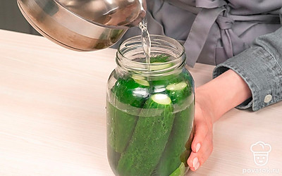 Заполните банки огурцами и пряностями. В подготовленные банки положите листья смородины, вишни, хрена, зонтики укропа, горошины душистого перца, лавровый лист и чеснок. Уложите огурцы, размещая плоды большего размера вертикально, а меньшего сверху.