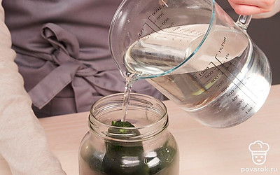 Простерилизуйте огурцы с зеленью и укропом. В каждую банку положите по несколько листиков смородины, хрена, вишни, дуба, укропа и 2-3 зубчика чеснока. Плотно уложите огурцы. Залейте банки с огурцами крутым кипятком на 5-10 минут, затем кипяток слейте.