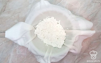 Дуршлаг устелите тканью, а сам дуршлаг установите так, чтобы стекшая сыроватка не касалась его дна. Затем слейте образовавшуюся сыроватку через ткань и дайте немного остыть творогу.