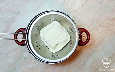 Получившийся творог заверните в ткань и сверху установите гнет. Отправьте в холодильник на 5-6 часов.