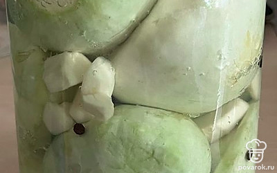 Выложите в банку нарезанный корень хрена, чеснок, перец горошком и плотно уложите патиссоны. Залейте кипятком и оставьте на 15 минут.