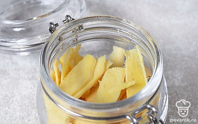С помощью терки для нарезки слайсами нарежьте корень имбиря на тонкие пластинки размером от 2 до 4 см. Выложите имбирь в простерилизованную банку.