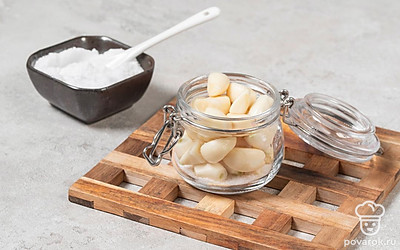 В подготовленную для засолки баночку насыпьте соль. Затем плотно уложите в банку весь чеснок.