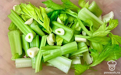 Уложите сельдерей в контейнер или банку, добавьте к нему чеснок, нарезанный пластинками.