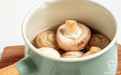 Отварите шампиньоны. В кастрюлю выложите шампиньоны, залейте 500 мл воды, вскипятите и варите на слабом огне 7 минут. Затем откиньте грибы на дуршлаг.