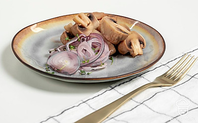 Порцию маринованных шампиньонов выложите на тарелку, украсьте красным луком и веточками укропа.