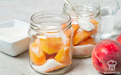 Подготовьте основу консервации. Подготовленные плоды персиков аккуратно уложите на дно подготовленной емкости разрезом вниз. Влейте от 1 до 4 ст. л. горячей воды, засыпьте сахар.