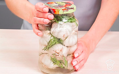 Наполните банки продуктами и отправьте чеснок на маринование. В банки уложите слоями чеснок и тархун. Залейте тару маринадом, закройте крышками и оставьте в сухом прохладном помещении на 14 дней.