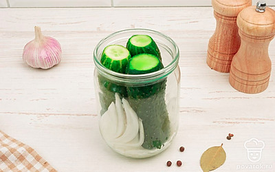 Срежьте с каждого огурца кончики. На дно банки положите лук, чеснок и затем огурцы и залейте горячим рассолом.