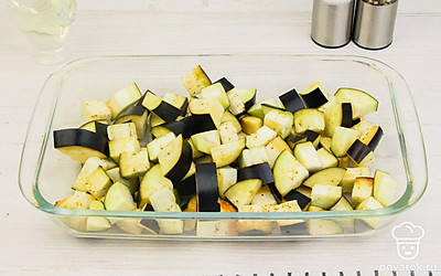 Нарезанные баклажаны переложите в открытую емкость (хорошо подойдет стеклянная форма для запекания), посолите (1 ч.л.) и оставьте на 1 час, чтобы ушла горечь. После этого промойте их и просушите, верните в форму для запекания, сбрызните маслом и отправьте в разогретую духовку на 15-20 минут.