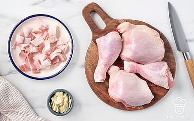 Нарежьте бекон кубиками со стороной 5-6 мм. Нашинкуйте чеснок тонкими пластинками. Разрежьте куриные окорочка на 2-3 части.