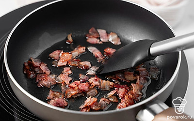 Разогрейте сухую сковороду на сильном огне. Выложите в нее кубики бекона и жарьте их, постоянно помешивая, пока весь жир не вытопится, а сам бекон не станет сухим и хрустящим. Уберите кусочки бекона со сковороды на тарелку.