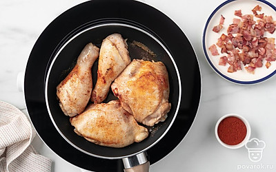 Уменьшите огонь под сковородой до среднего и выложите в оставшийся от бекона жир сливочное масло. Подождите, когда оно растает, и положите в смесь масла и жира кусочки курицы. Приправьте их паприкой и обжарьте со всех сторон в течение 6-7 минут до плотной румяной корочки.