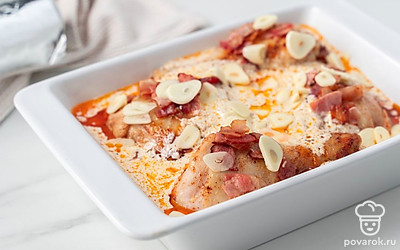 Разогрейте духовку до 180°C. Полейте сливочным соусом курицу в форме для запекания, разложите сверху пластинки чеснока. Закройте форму фольгой и запекайте курицу в течение 40 минут. Разверните фольгу, подрумяньте курицу в духовке еще 5-10 минут.