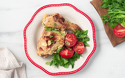 Подайте сочную чесночную курицу с помидорами черри, листьями салата, посыпав их зеленым луком и полив соусом из формы для запекания.