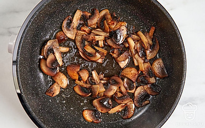 Разогрейте сковороду с 25 г сливочного масла. Нарежьте шампиньоны тонкими пластинами или мелкими кубиками и выложите в разогретую сковороду. Обжарьте грибы в течение 10-15 минут.