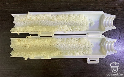 Выложите рис в форму для приготовления роллов, сделав выемки для начинки.