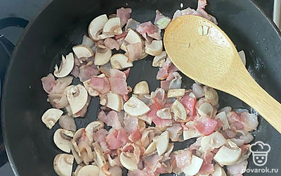 В сковороде обжарьте нарезанные бекон и грибы. 