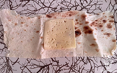 Разложите лаваш, сверху положите ломтик сыра.